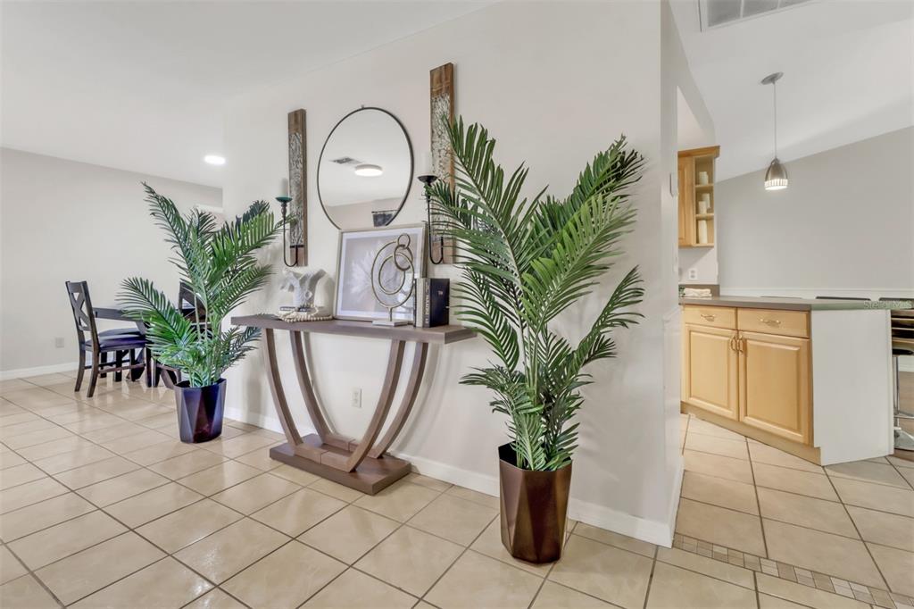 A console table with a mirror and two potted palm plants sits in a tiled entryway — 4800 SW 12TH PLACE, CAPE CORAL, FL