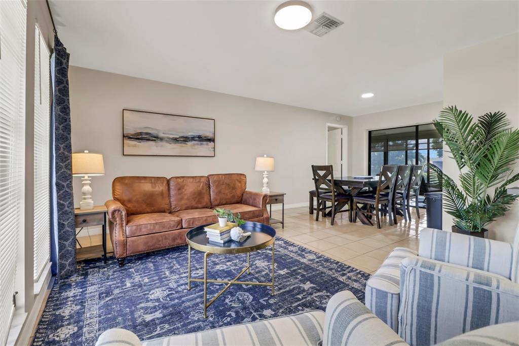 A living room features a leather sofa, blue patterned rug, and an adjacent dining area — 4800 SW 12TH PLACE, CAPE CORAL, FL