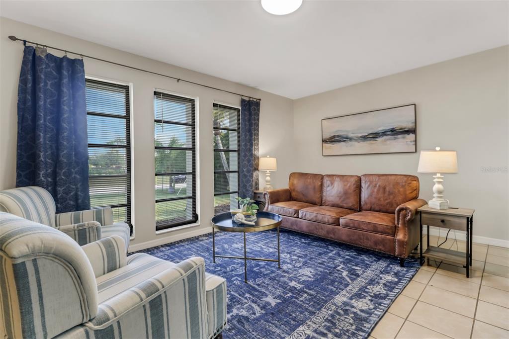 A living room features a leather sofa, striped armchairs, a blue rug, and three windows — 4800 SW 12TH PLACE, CAPE CORAL, FL