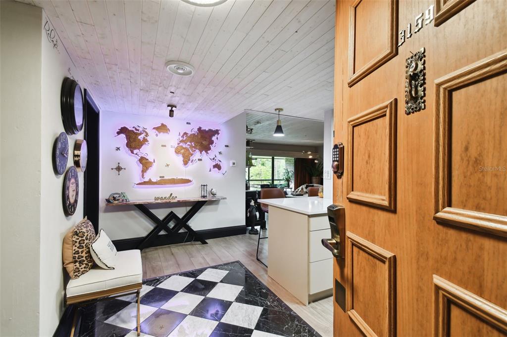 An entryway features a checkered floor, a world map wall art, and a wooden door — 36750 US HIGHWAY 19 N UNIT 20305, PALM HARBOR, FL