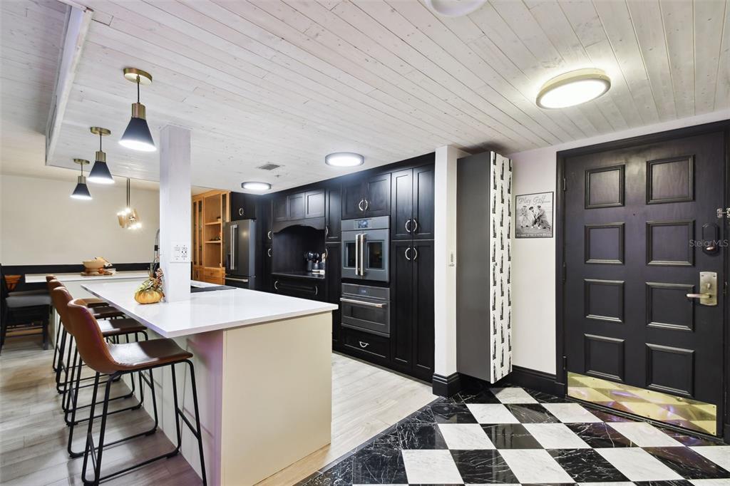 A kitchen features black cabinets, a white island, and a black and white checkered floor — 36750 US HIGHWAY 19 N UNIT 20305, PALM HARBOR, FL