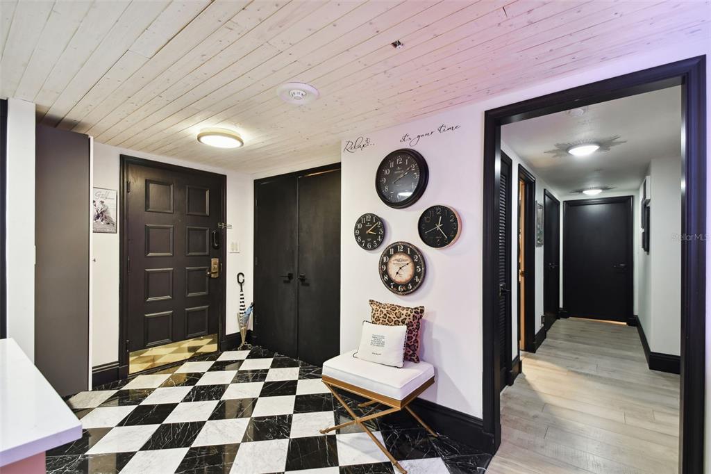 An entryway features a black and white checkered floor, black doors, and four wall clocks — 36750 US HIGHWAY 19 N UNIT 20305, PALM HARBOR, FL