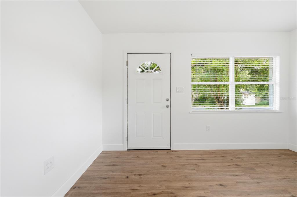 A room with white walls, wood-look flooring, a white front door, and a window — 1009 NEBRASKA STREET, LEESBURG, FL