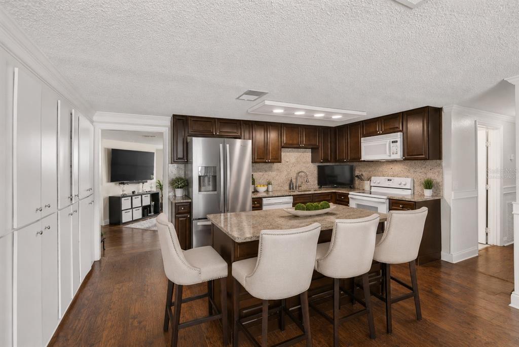 A kitchen features a dark wood island with a granite countertop and white storage cabinets — 918 JERE CIRCLE, LAKELAND, FL