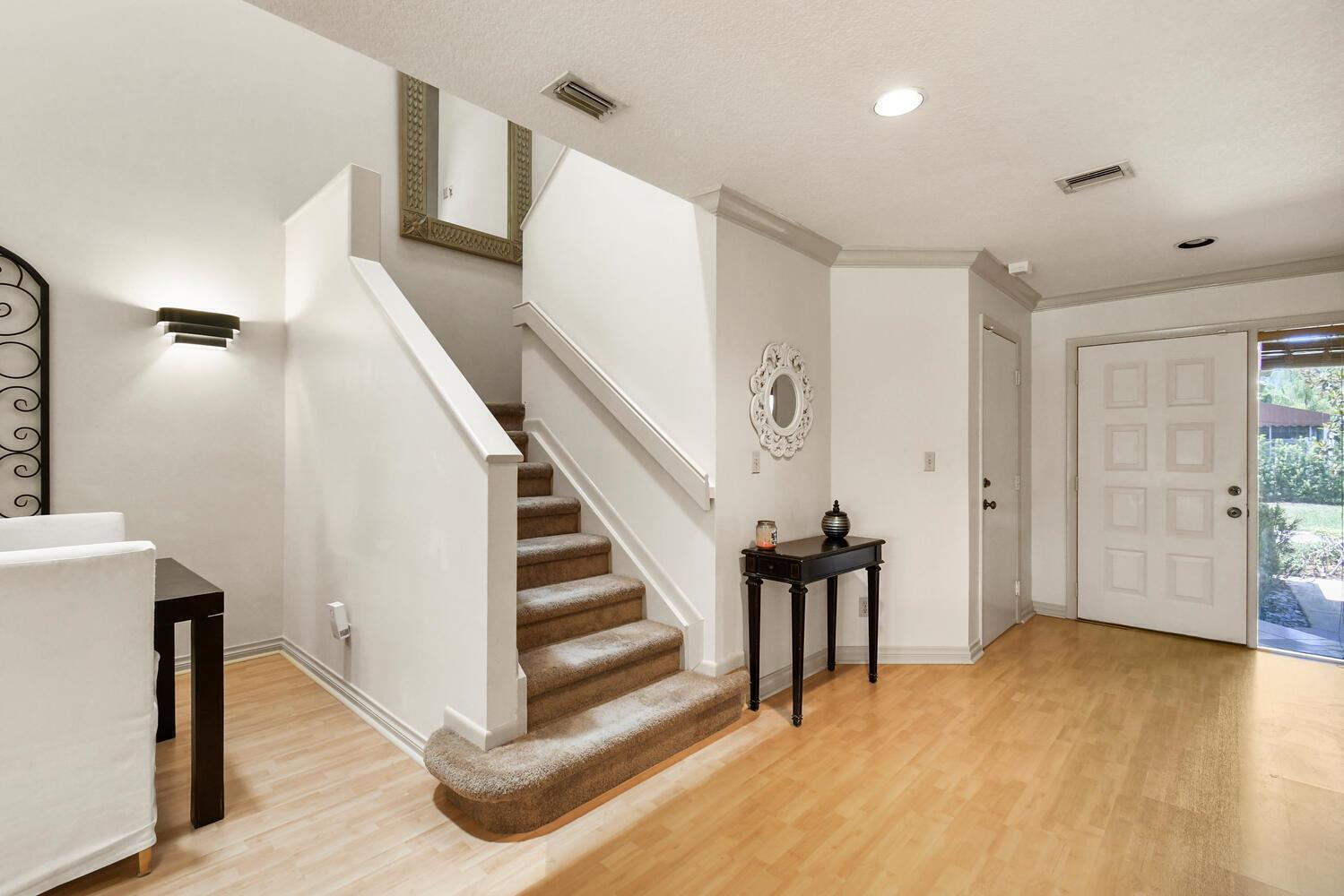 An entryway features light wood flooring, a carpeted staircase, and a white front door — 5266 Sapphire Valley, Boca Raton FL 33486, BOCA RATON, FL