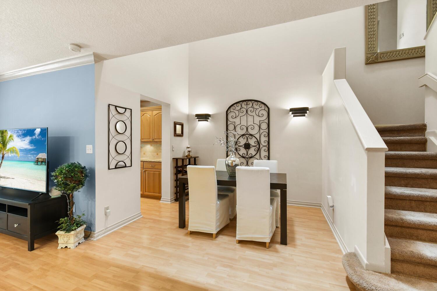 A dining area with a dark table, white chairs, and wall art near a staircase — 5266 Sapphire Valley, Boca Raton FL 33486, BOCA RATON, FL