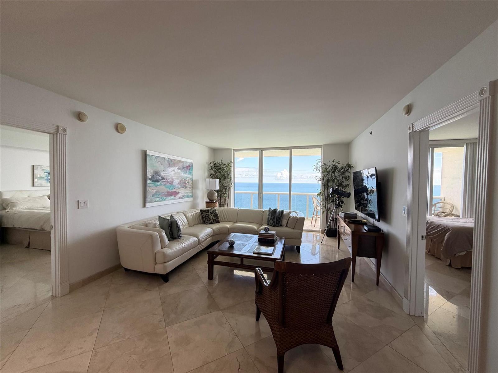 A living room with a white sectional sofa, tile floors, and a view of the ocean — 1850 S Ocean Drive # 4202, Hallandale Beach FL 33009, HALLANDALE BEACH, FL