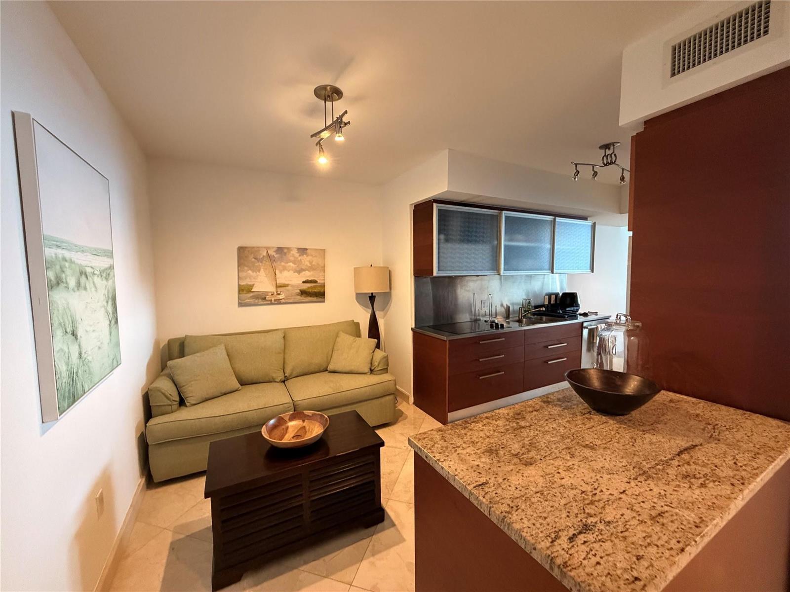 A small living area with a green sofa sits adjacent to a kitchen with cabinets — 1850 S Ocean Drive # 4202, Hallandale Beach FL 33009, HALLANDALE BEACH, FL