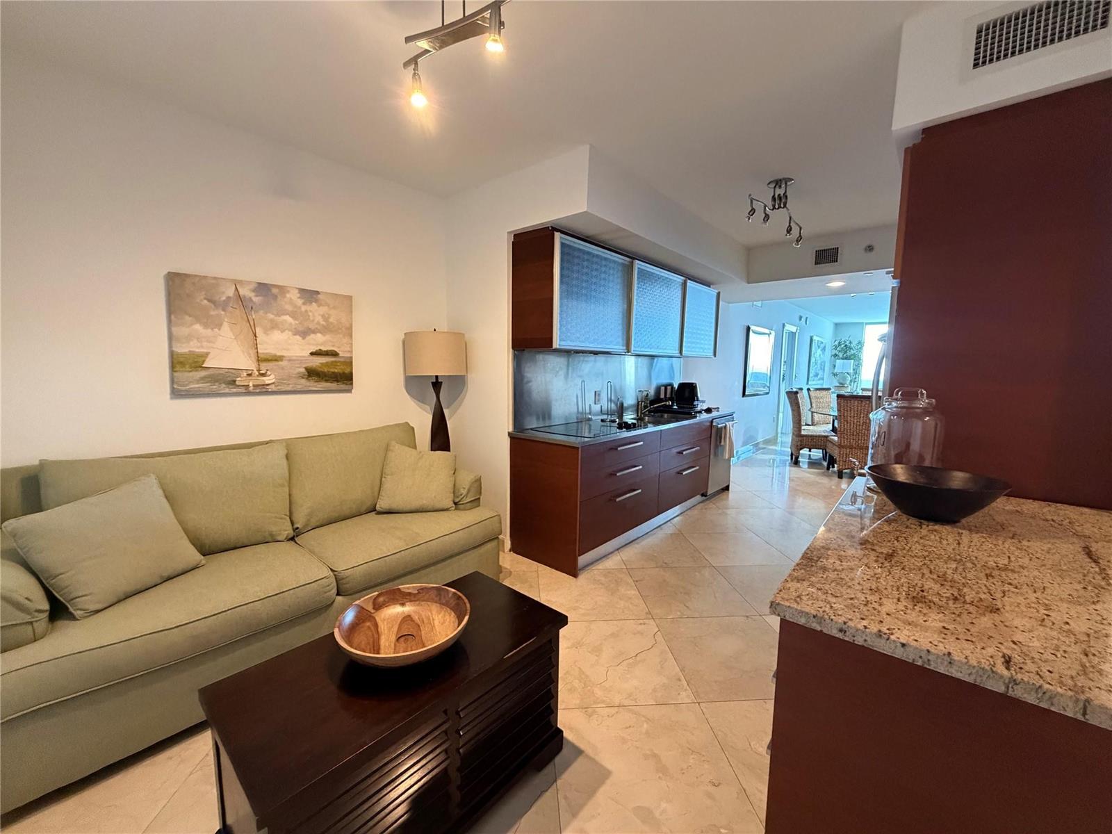 A living room with a green sofa and coffee table adjacent to a galley kitchen — 1850 S Ocean Drive # 4202, Hallandale Beach FL 33009, HALLANDALE BEACH, FL
