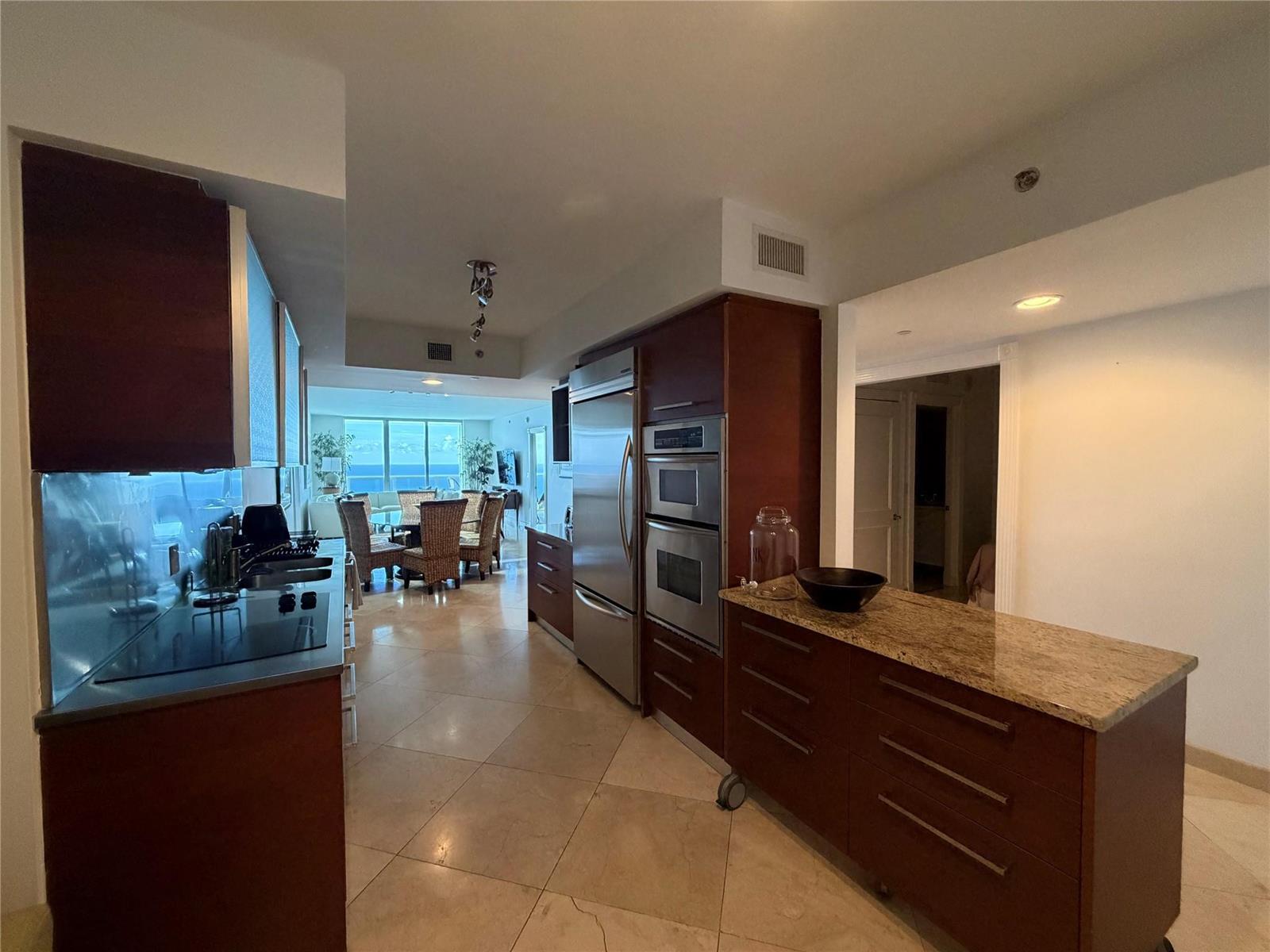 A kitchen with dark wood cabinetry, stainless steel appliances, and a granite-topped rolling island — 1850 S Ocean Drive # 4202, Hallandale Beach FL 33009, HALLANDALE BEACH, FL