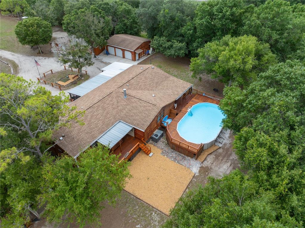 An aerial view shows a house with a wooden deck, above-ground pool, and detached garage — 17021 SHELBY LANE, NORTH FORT MYERS, FL