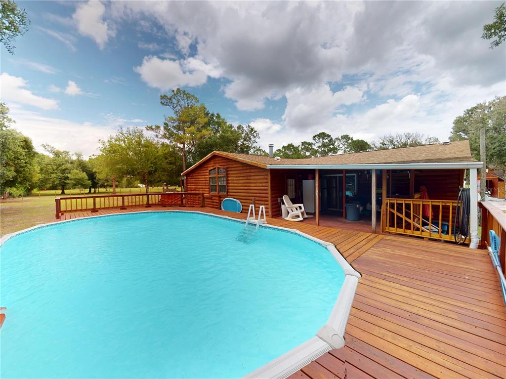 A wooden cabin with a large deck and an above-ground swimming pool in the backyard — 17021 SHELBY LANE, NORTH FORT MYERS, FL