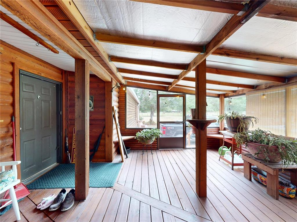 A covered wooden porch features log walls, a screen door, and potted plants — 17021 SHELBY LANE, NORTH FORT MYERS, FL