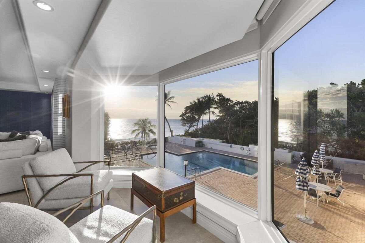 A living area with white armchairs overlooks a swimming pool and the ocean beyond — 4605 S Ocean Boulevard # 3b, Highland Beach FL 33487, HIGHLAND BEACH, FL