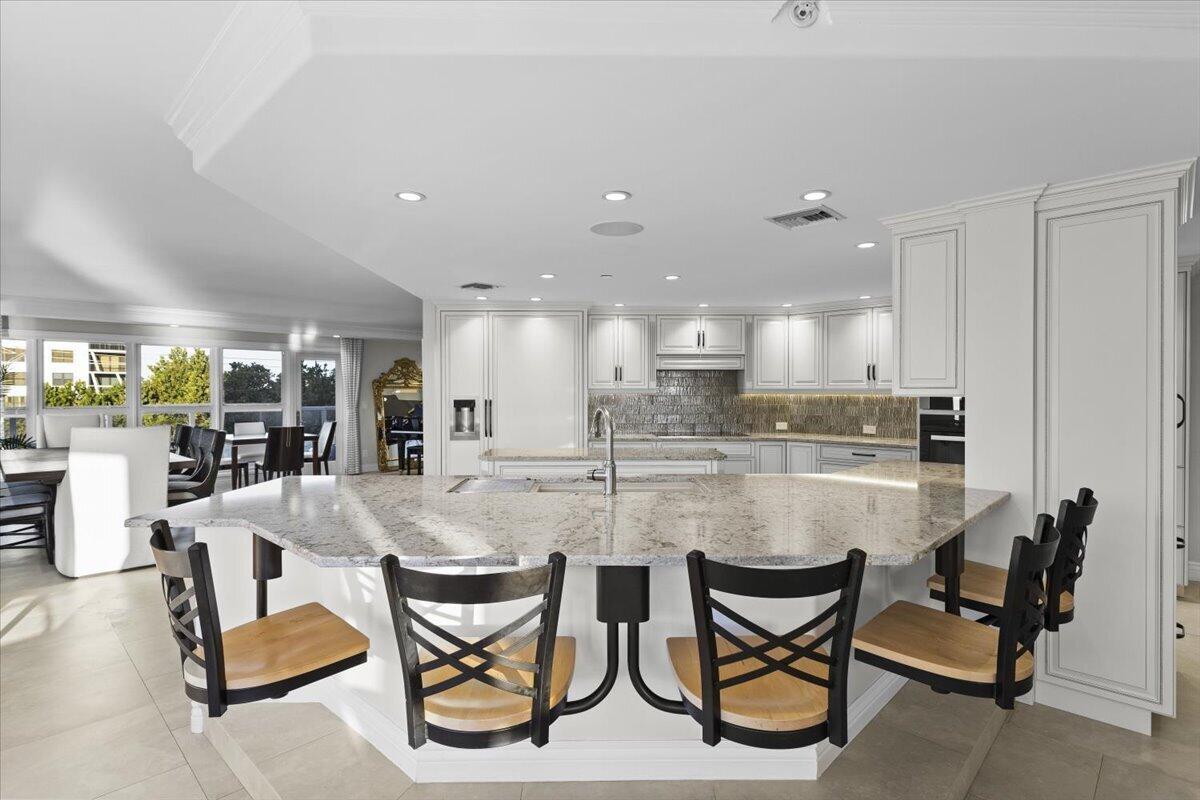 A spacious white kitchen features a large granite island with bar seating and recessed lighting — 4605 S Ocean Boulevard # 3b, Highland Beach FL 33487, HIGHLAND BEACH, FL