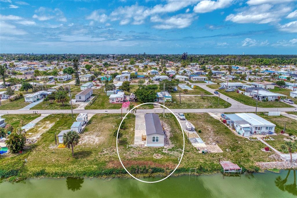 An aerial view shows a single-story mobile home situated on a waterfront lot — 1391 FLAMINGO DRIVE, ENGLEWOOD, FL