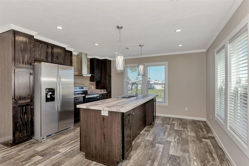 A kitchen features dark wood cabinets, a stainless steel refrigerator, and a central island — 1391 FLAMINGO DRIVE, ENGLEWOOD, FL