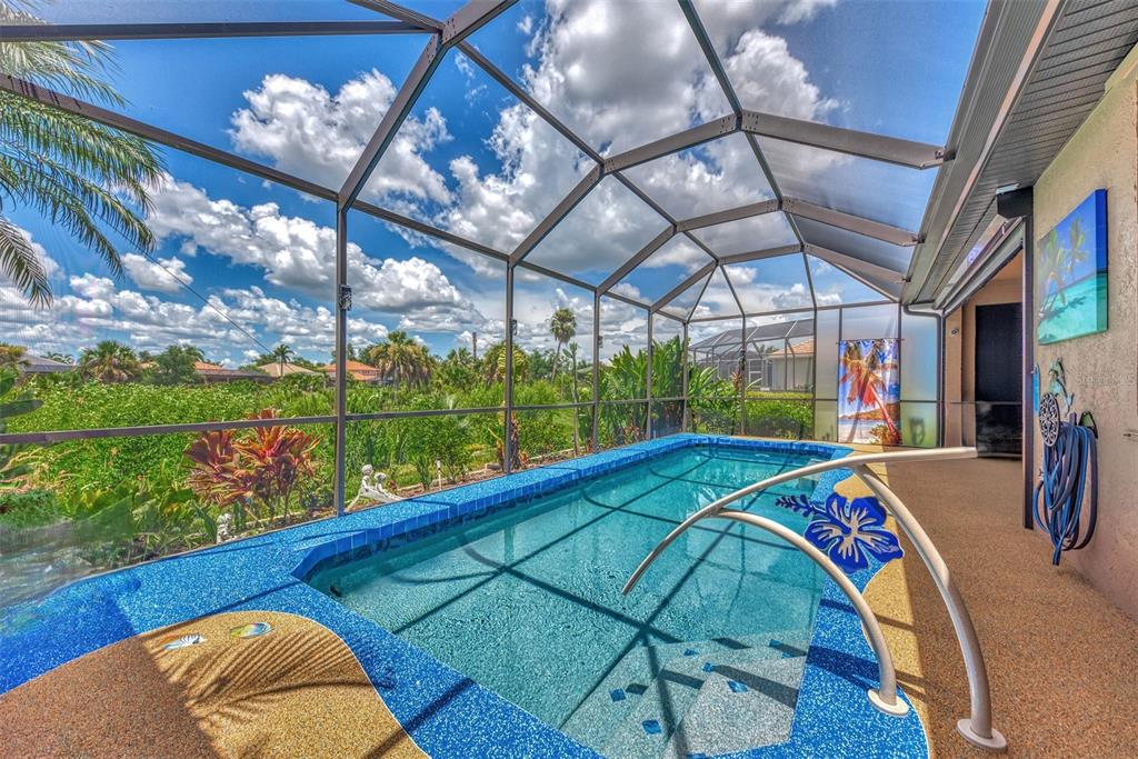 A screened-in pool area features a blue tiled pool with a metal handrail and deck — 3275 OSPREY LANE, PORT CHARLOTTE, FL