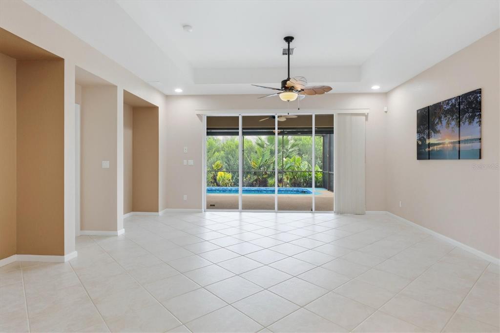A spacious living room with tile floors, a ceiling fan, and sliding doors to a pool — 3275 OSPREY LANE, PORT CHARLOTTE, FL