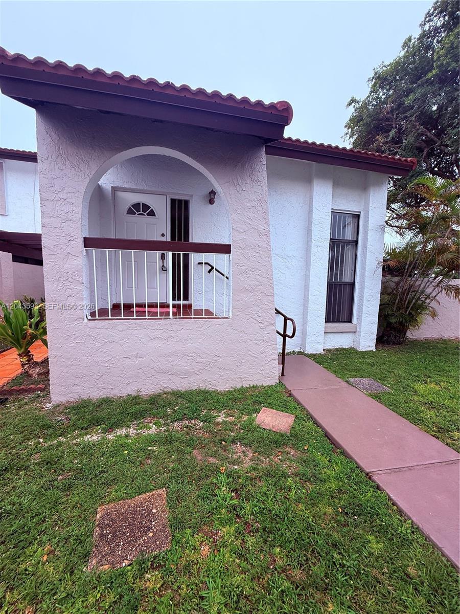 The exterior of a single-story home features a covered entryway with a white railing — 9909 NW 9th St Cir # 3, Miami FL 33172, MIAMI, FL