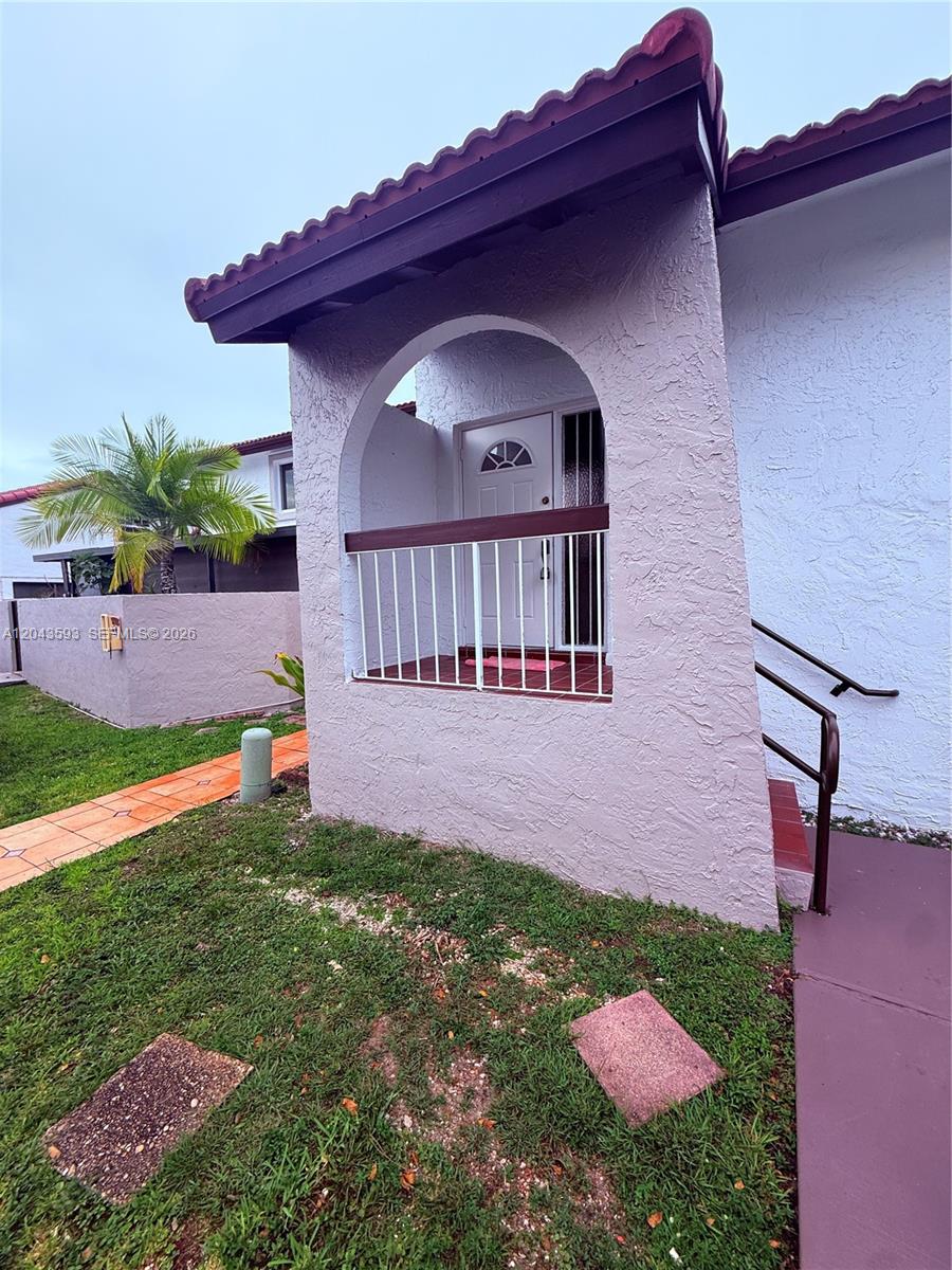 The exterior of a house features a covered entryway with a white door and railing — 9909 NW 9th St Cir # 3, Miami FL 33172, MIAMI, FL