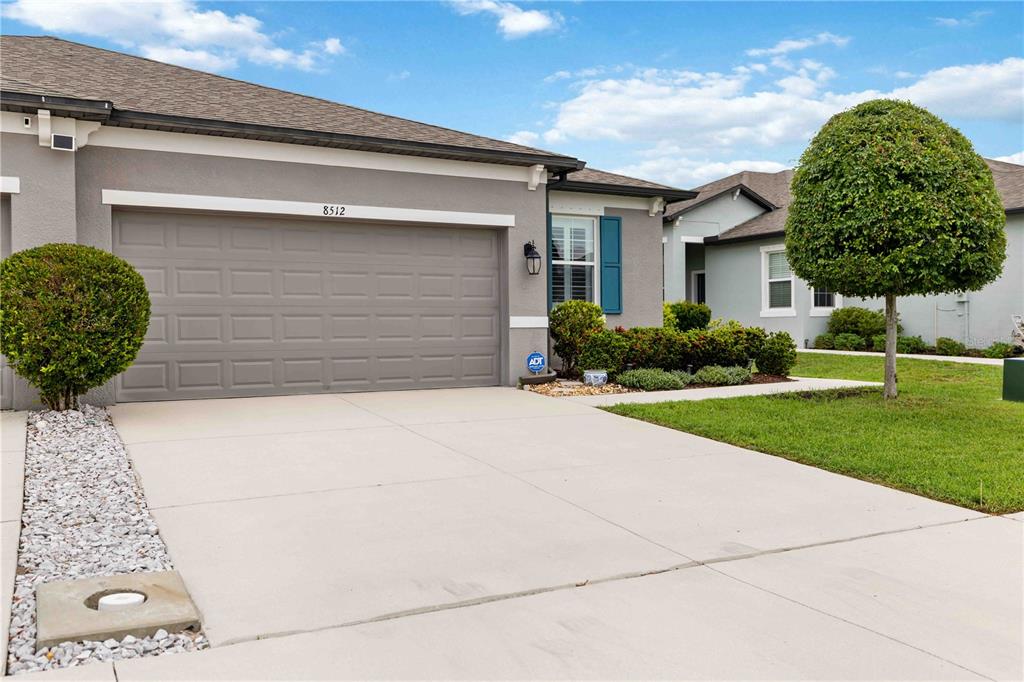 A gray house with a two-car garage, a concrete driveway, and a manicured front lawn — 8512 CACHE DRIVE, SARASOTA, FL