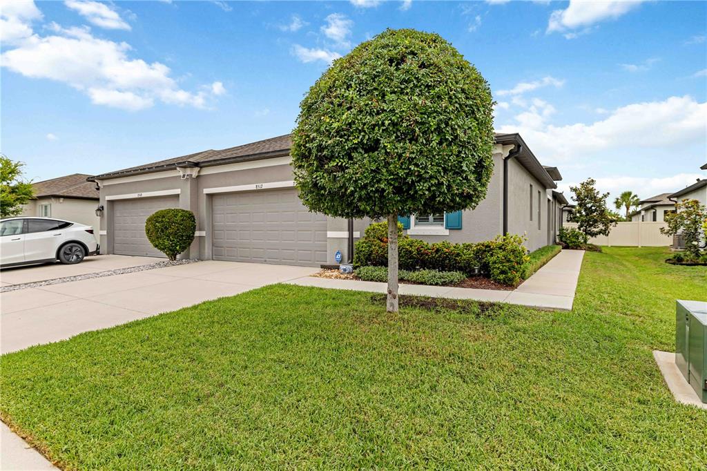 A gray single-story house with a two-car garage and a manicured tree in front — 8512 CACHE DRIVE, SARASOTA, FL
