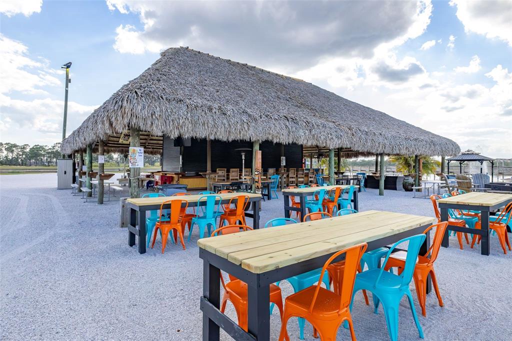 An outdoor tiki bar features a thatched roof, gravel ground, and colorful metal chairs — 330 CR-630, LAKE WALES, FL