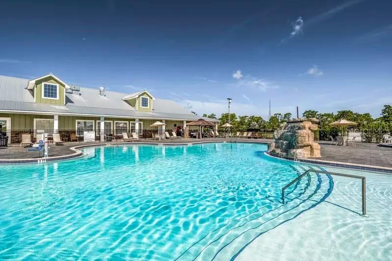 A swimming pool with a rock water feature sits in front of a community building — 330 CR-630, LAKE WALES, FL
