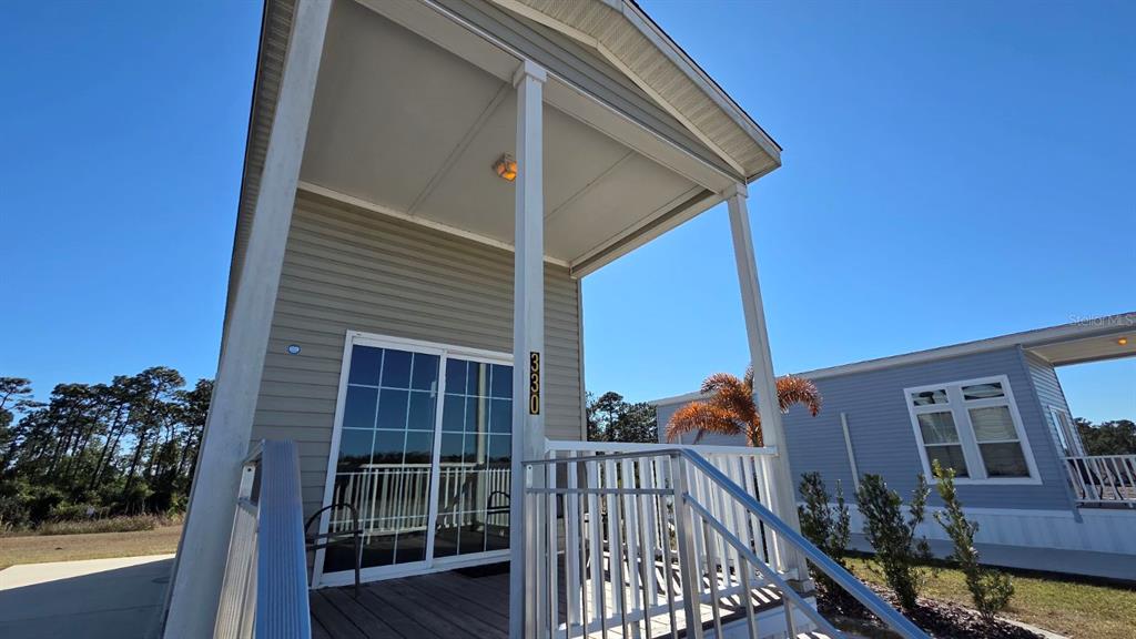 A low-angle view of a mobile home exterior featuring a covered porch and sliding doors — 330 CR-630, LAKE WALES, FL