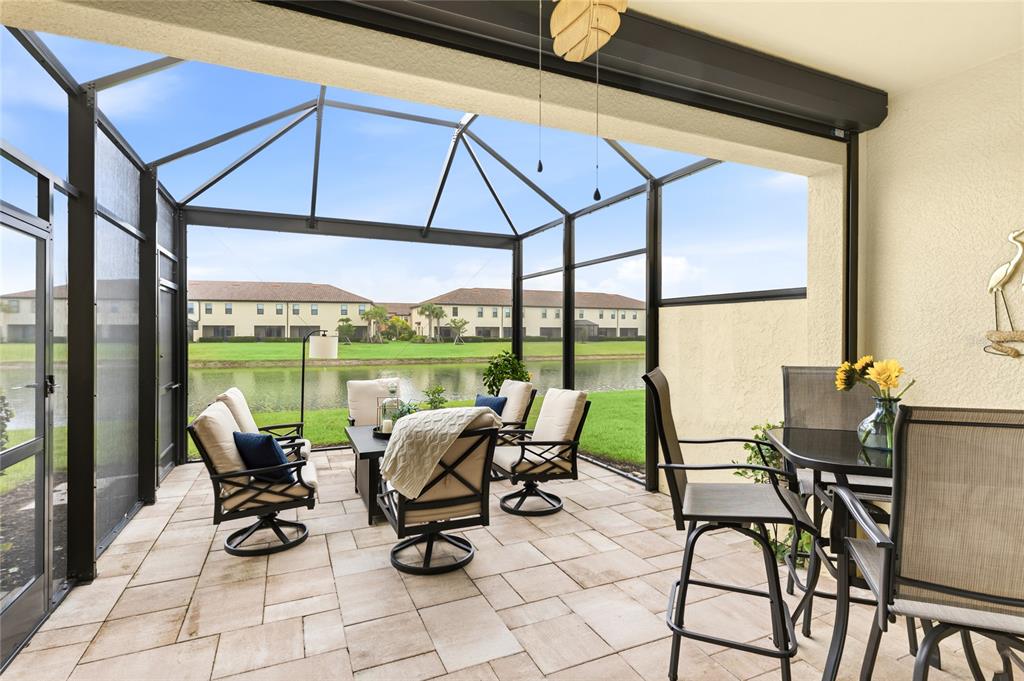 A screened-in patio features tile flooring, outdoor furniture, and a view of a pond — 20185 LAGENTE CIRCLE, VENICE, FL