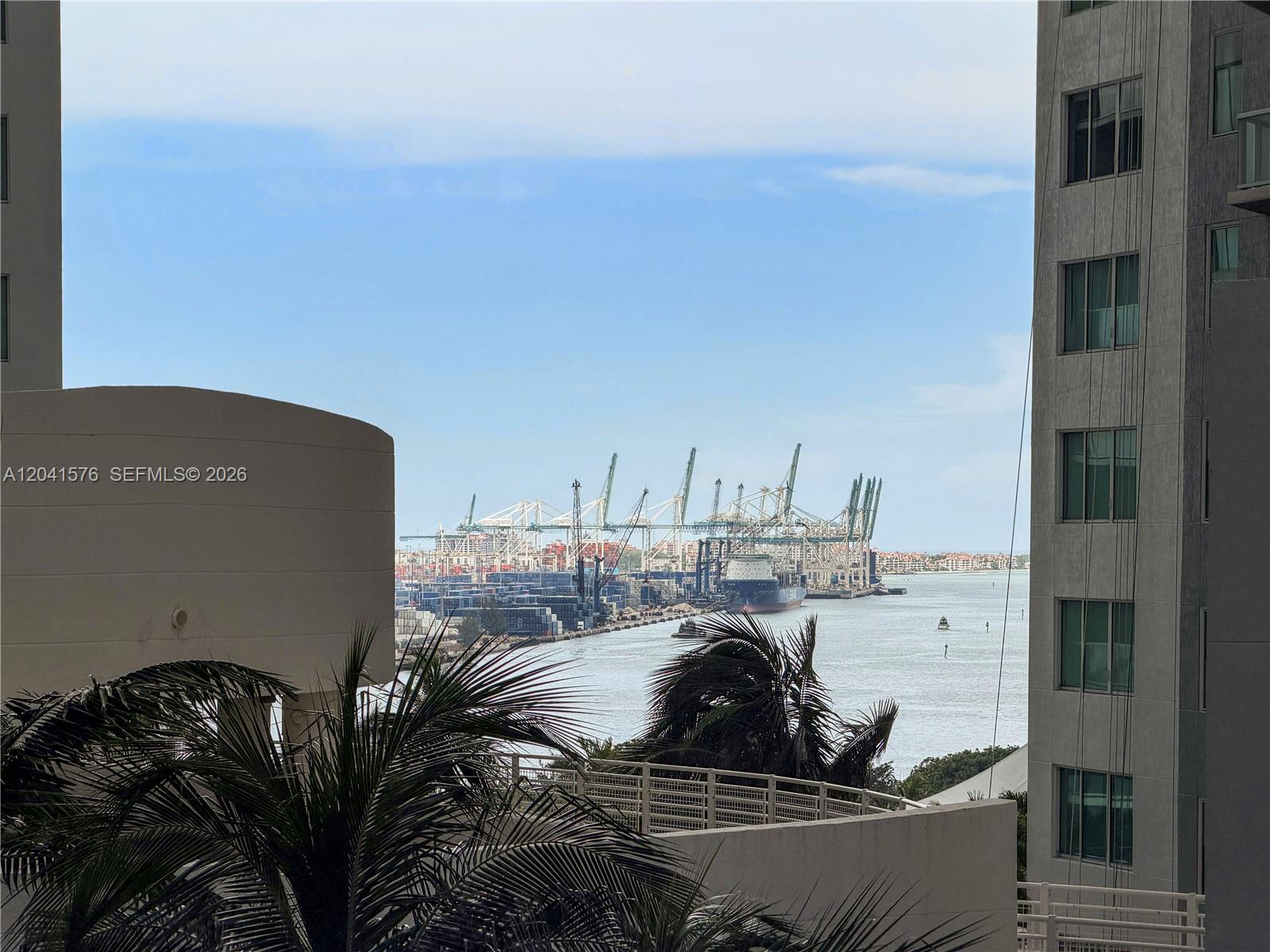 A view from a balcony overlooks a shipping port with cranes and a cargo ship — 234 NE 3rd St # 1404, Miami FL 33132, MIAMI, FL