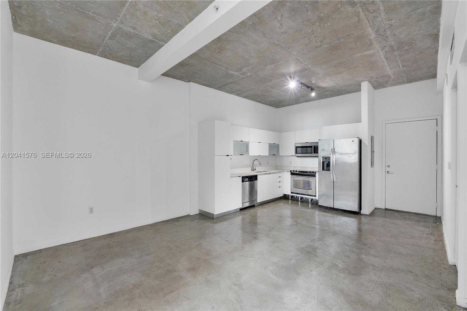 A kitchen with white cabinets and stainless steel appliances sits on a concrete floor — 234 NE 3rd St # 1404, Miami FL 33132, MIAMI, FL
