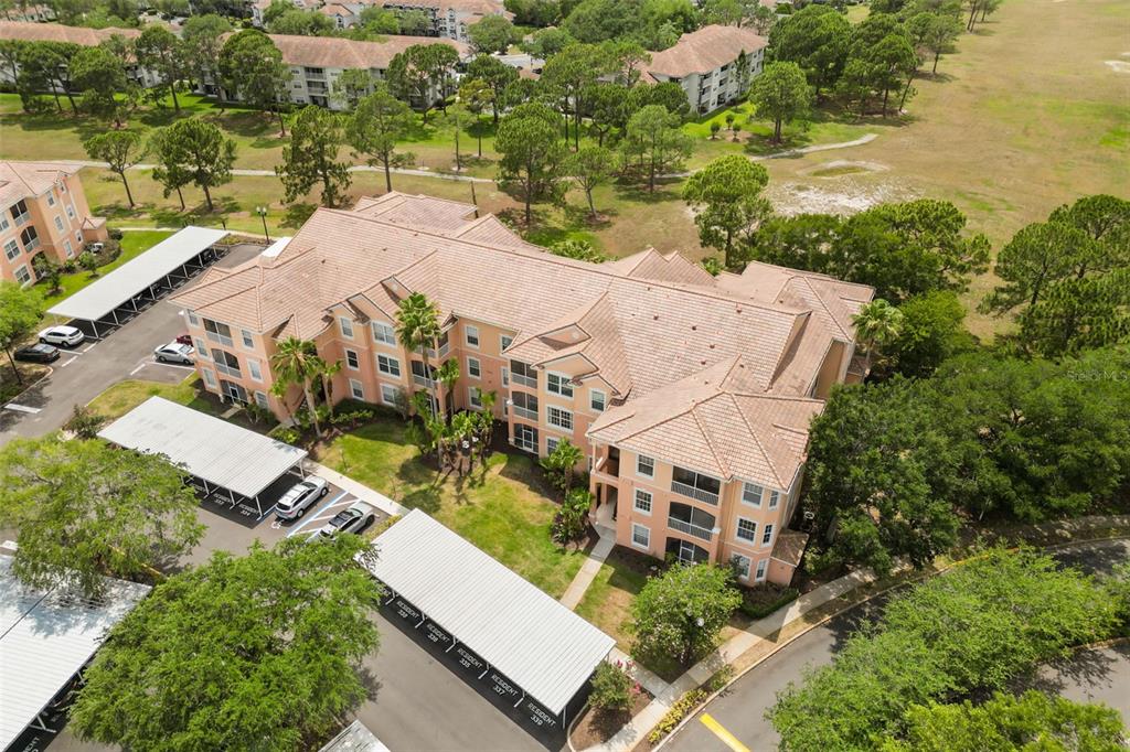 An aerial view shows a multi-story apartment building with a tiled roof and parking carports — 13500 TURTLE MARSH LOOP UNIT 823, ORLANDO, FL