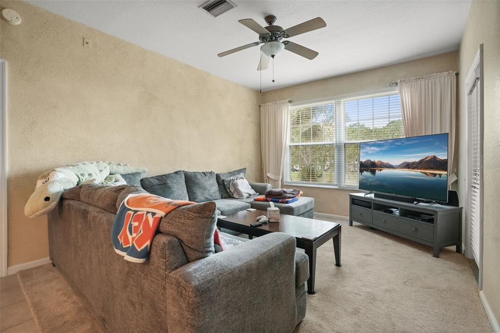A living room features a gray sectional sofa, a coffee table, and a television console — 13500 TURTLE MARSH LOOP UNIT 823, ORLANDO, FL