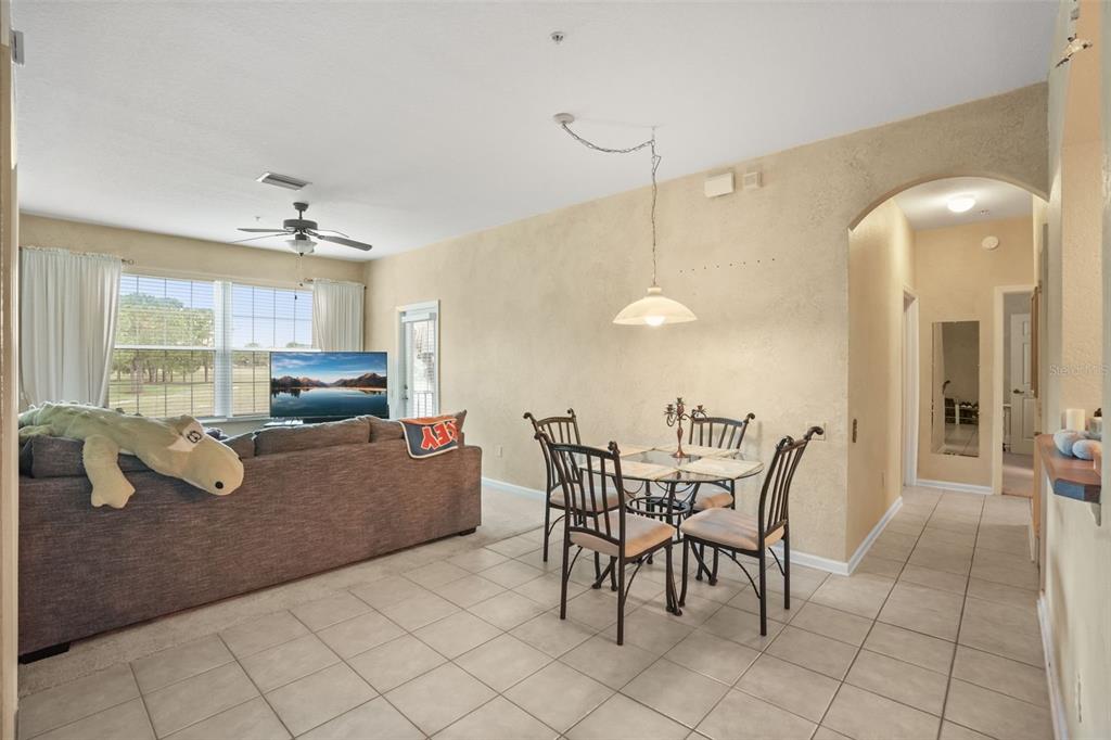 A living and dining area with tile flooring, a ceiling fan, and a glass table — 13500 TURTLE MARSH LOOP UNIT 823, ORLANDO, FL
