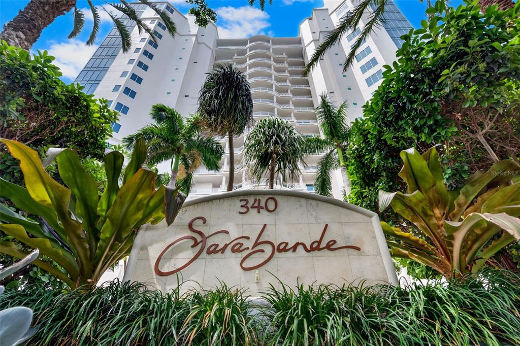 A low-angle shot shows the exterior of the Sarabande condominium building behind a stone sign — 340 S PALM AVENUE UNIT 14, SARASOTA, FL