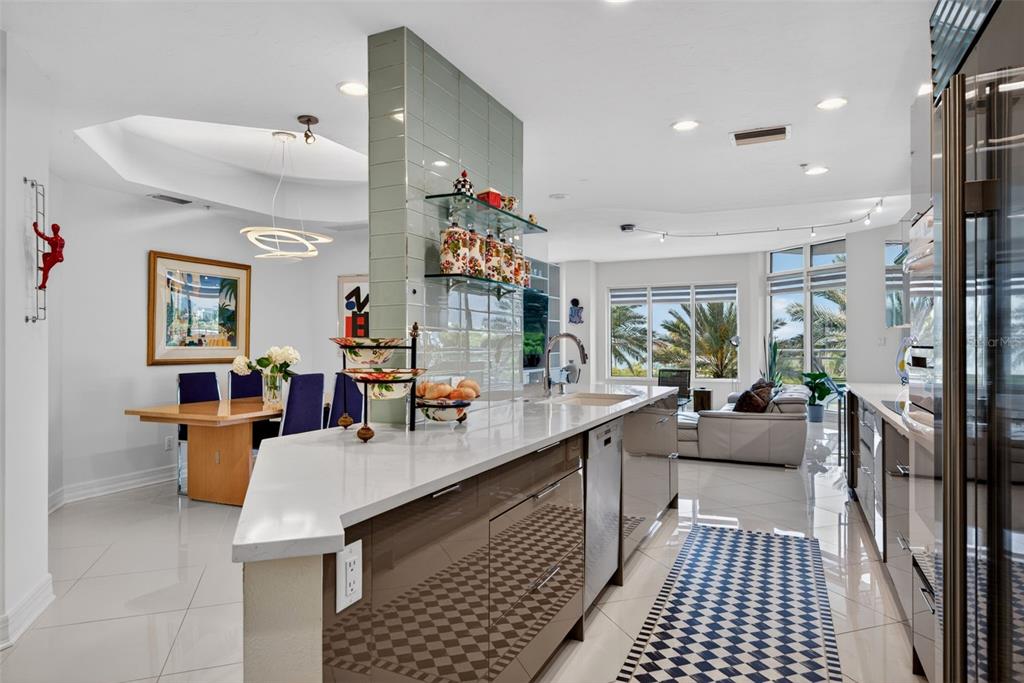 A modern kitchen with glossy cabinets, a white countertop, and a dining area nearby — 340 S PALM AVENUE UNIT 14, SARASOTA, FL