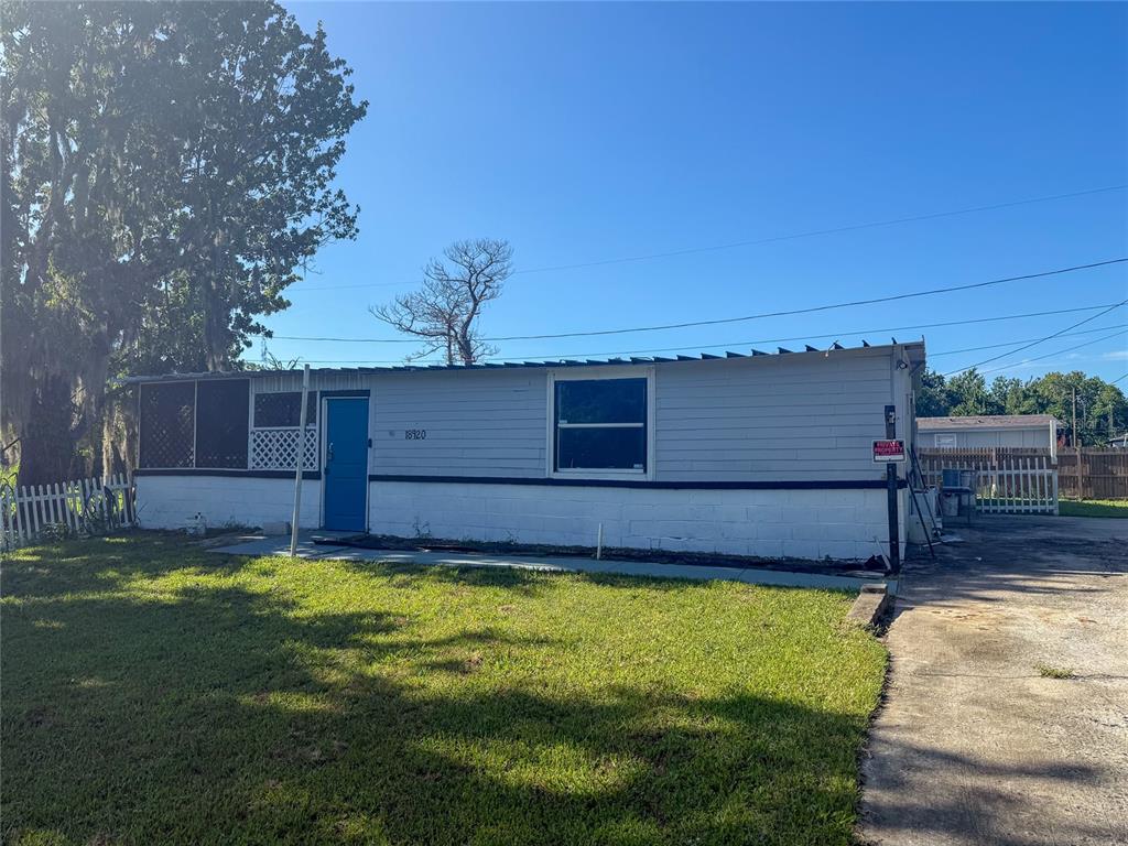 A single-story house with gray siding, a blue door, and a white block foundation — 18920 3RD AVENUE, ORLANDO, FL