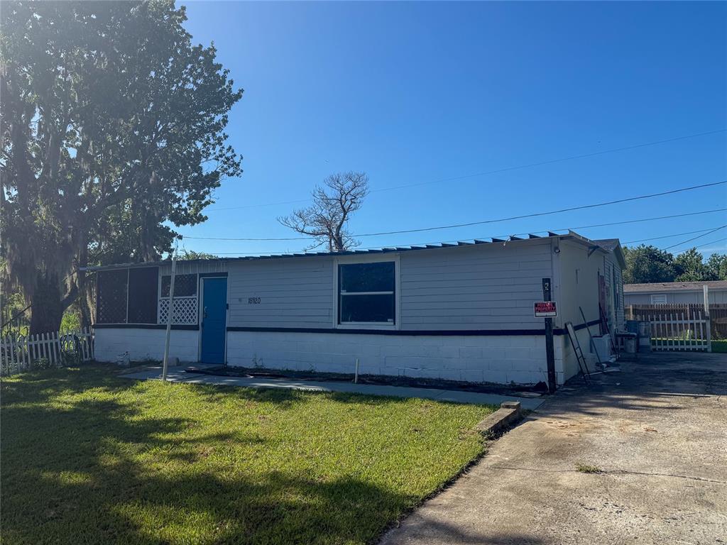 A single-story house with light gray siding, a blue door, and a concrete driveway — 18920 3RD AVENUE, ORLANDO, FL