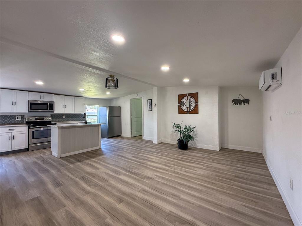 A kitchen with white cabinets and stainless steel appliances opens into a living area — 18920 3RD AVENUE, ORLANDO, FL