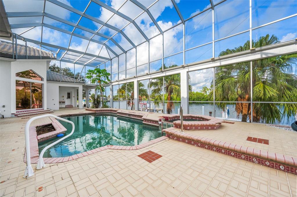 An enclosed swimming pool and hot tub area with a view of the water — 4323 ROCK CREEK DRIVE, PORT CHARLOTTE, FL