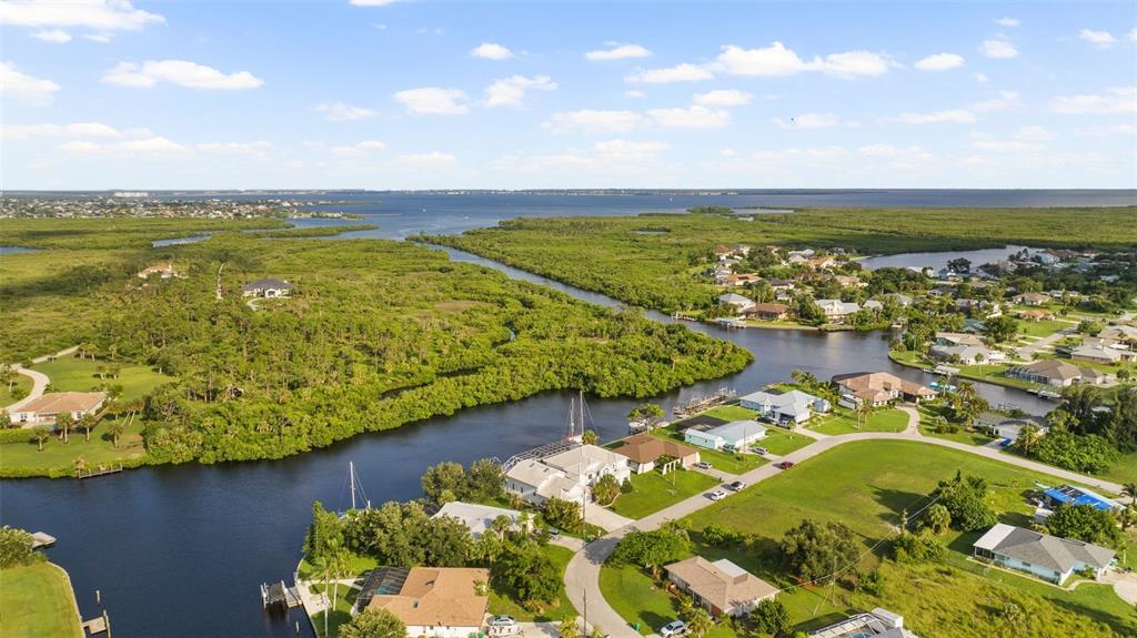 An aerial view shows houses along a canal surrounded by dense green vegetation and water — 4323 ROCK CREEK DRIVE, PORT CHARLOTTE, FL