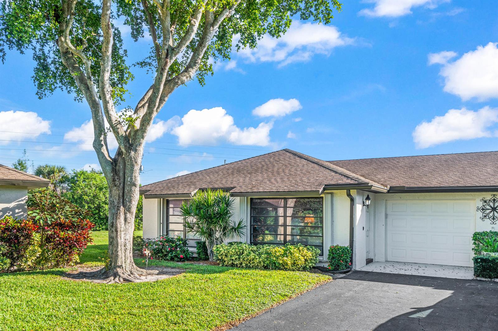 A single-story house with a brown shingled roof, a white garage door, and a large tree — 4868 Hawkwood Road # A, Boynton Beach FL 33436, BOYNTON BEACH, FL