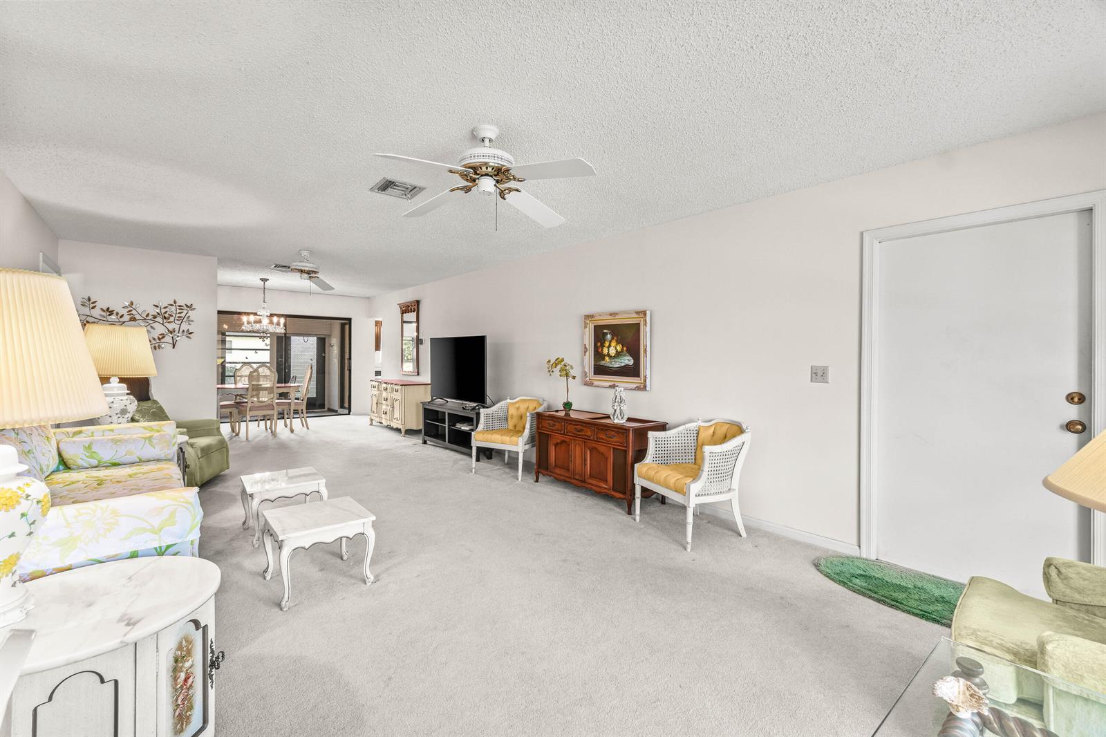 A living room with carpeted floors, a ceiling fan, and a dining area in the back — 4868 Hawkwood Road # A, Boynton Beach FL 33436, BOYNTON BEACH, FL