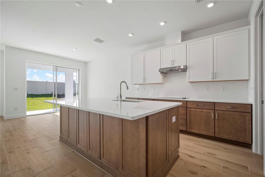 A kitchen features a large island, white upper cabinets, brown lower cabinets, and tile flooring — 2945 STEWART CREEK CIRCLE, PLANT CITY, FL