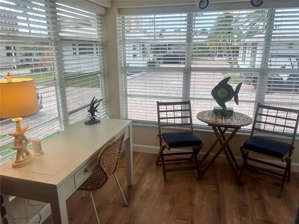 A sunroom features a white desk, a small wooden table with two chairs, and blinds — 6020 MIDNIGHT PASS ROAD UNIT 38, SARASOTA, FL