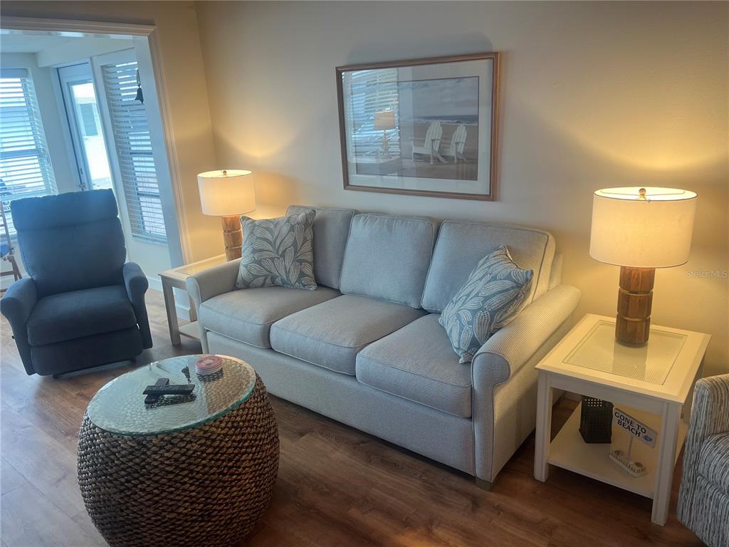 A living room features a light gray sofa, a round woven coffee table, and two lamps — 6020 MIDNIGHT PASS ROAD UNIT 38, SARASOTA, FL