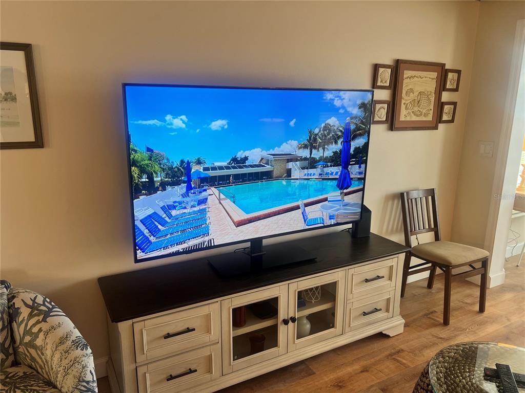A living room features a large wall-mounted television above a white and dark wood media console — 6020 MIDNIGHT PASS ROAD UNIT 38, SARASOTA, FL