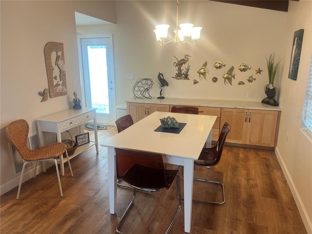A dining room features a white table, modern chairs, light wood cabinetry, and coastal decor — 6020 MIDNIGHT PASS ROAD UNIT 38, SARASOTA, FL